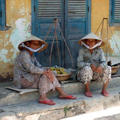 Twee reizigers met hoeden kijken uit over een rivierlandschap tijdens een groepsrondreis Vietnam kort.