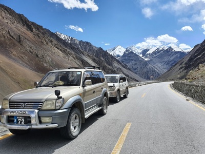 4x4’s op de Karakoram Highway in Hunza, met besneeuwde bergtoppen in Pakistan op de achtergrond.
