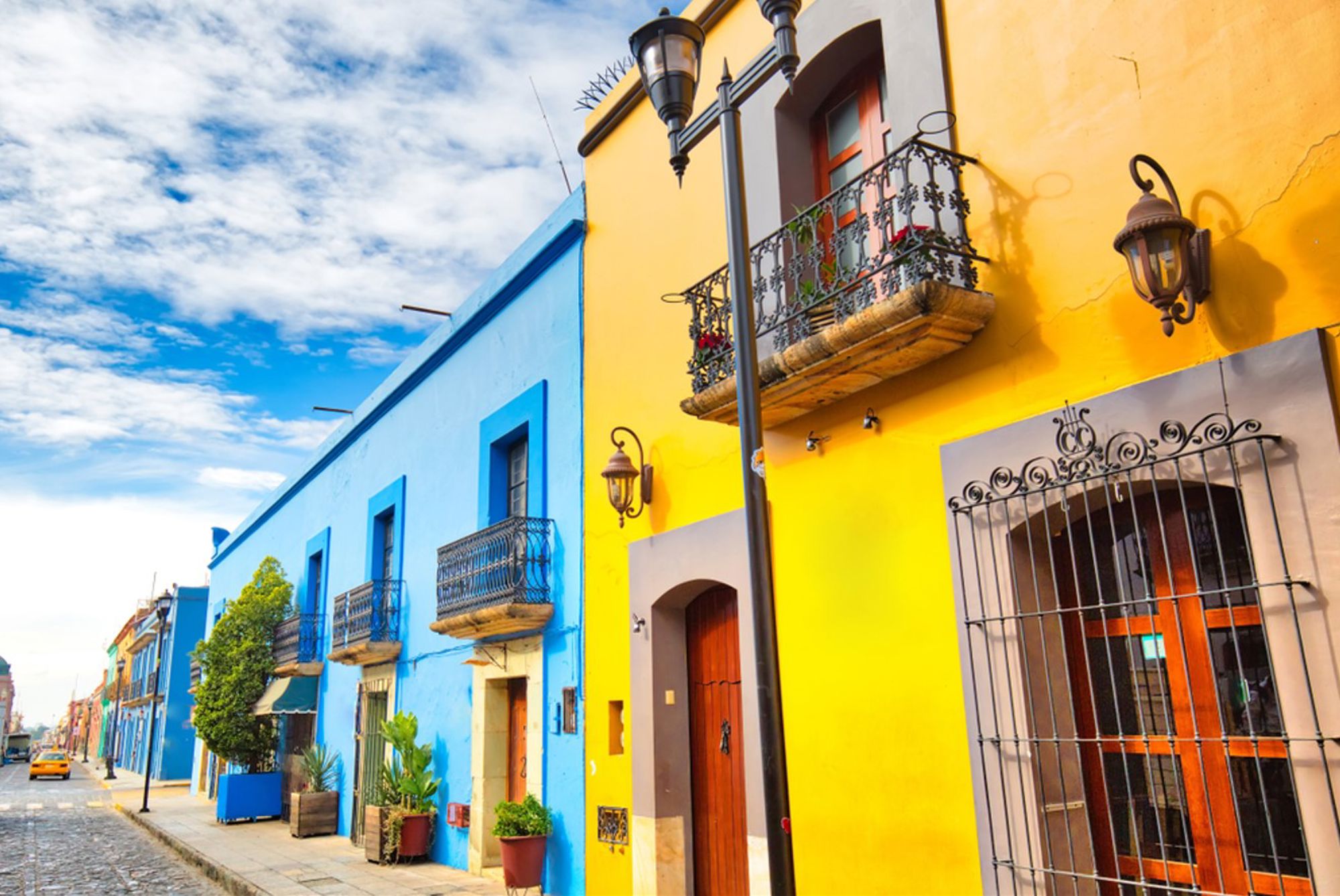 Kleurrijke straat met gele en blauwe gevels en sierlijke balkons in Mexico.