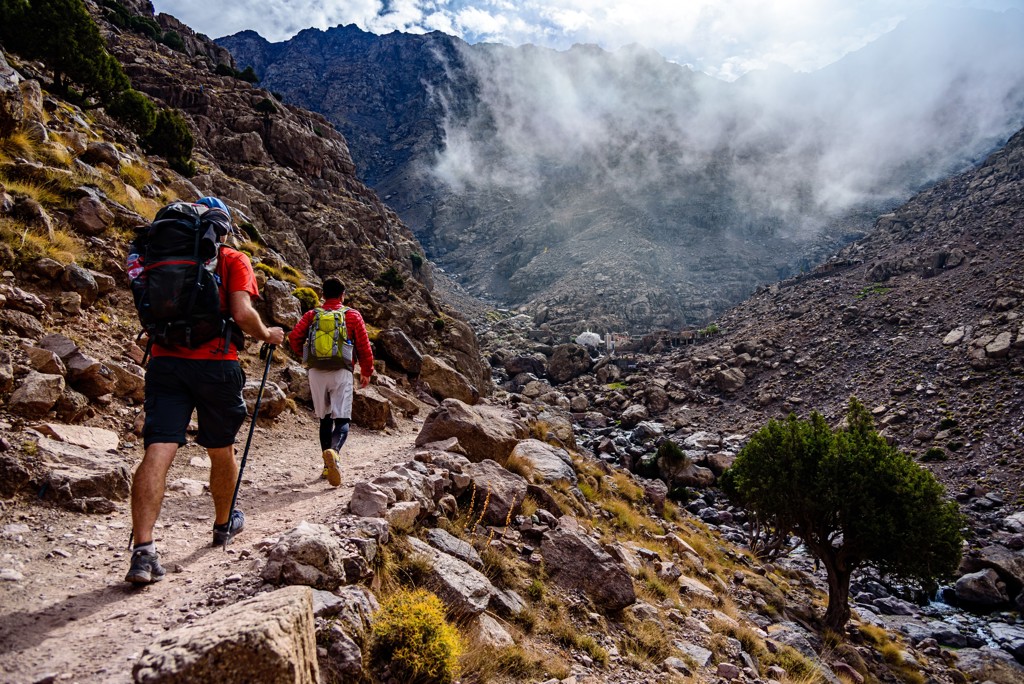 Wandelaars met rugzak op bergpad tijdens beklimming van Mount Toubkal in Marokko.