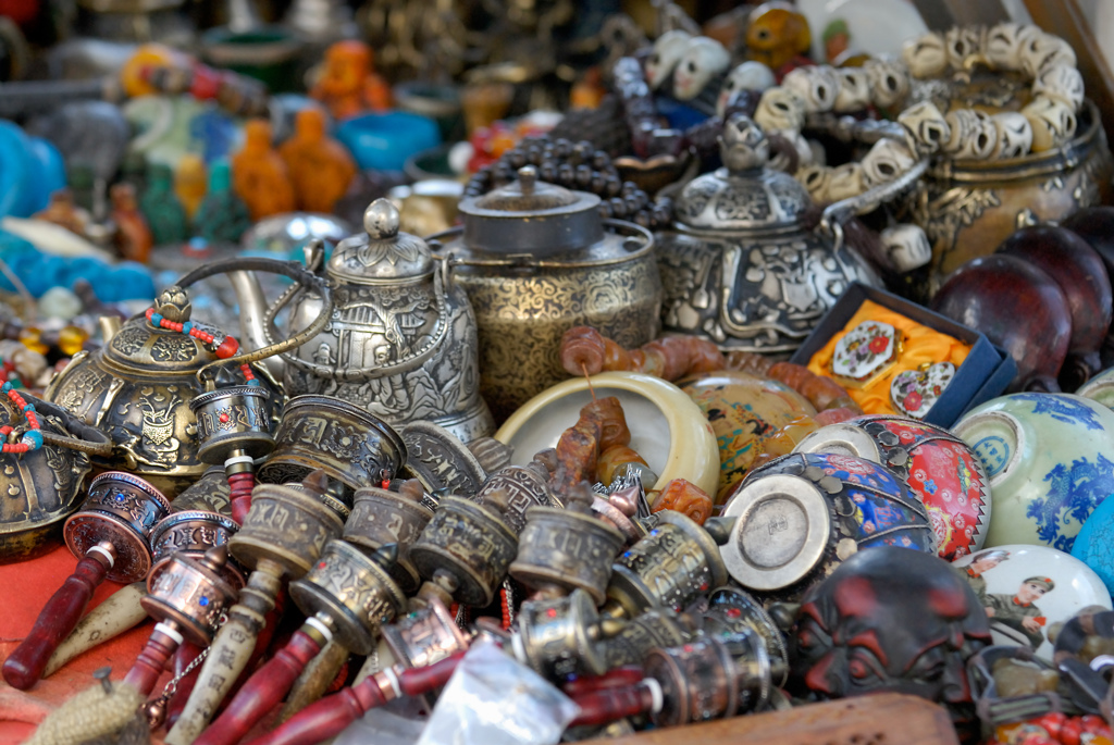 Tibetaanse souvenirs op een markt, met gebedsmolens, sieraden en metalen theepotten tijdens een groepsrondreis Tibet en Nepal.