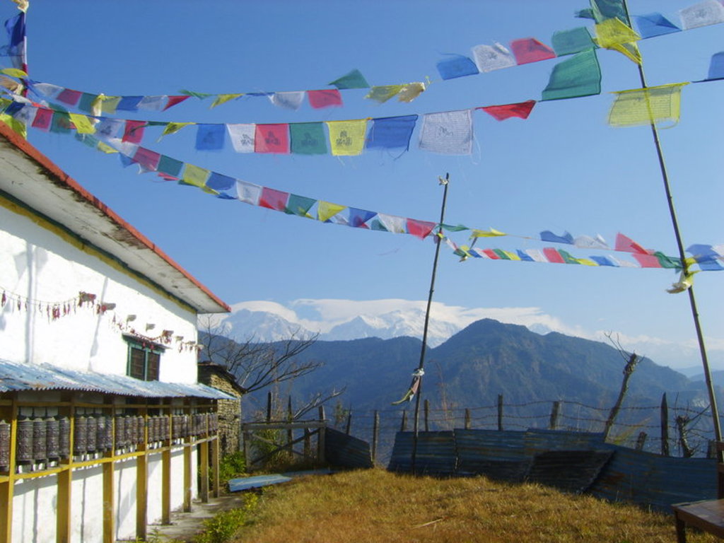 Gebedsvlaggen bij een lodge op de Annapurna Basecamp-trek in Nepal, met uitzicht op besneeuwde Himalayatoppen.