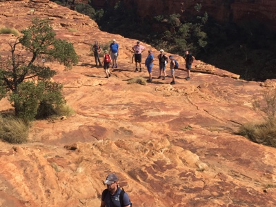 Wandelaars op rood zandsteenplateau met uitzicht op Kings Canyon in Australië.