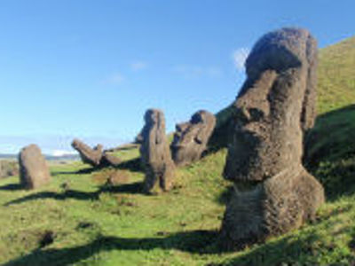 Moai-beelden op Paaseiland langs een groen heuvelpad onder een heldere blauwe lucht.