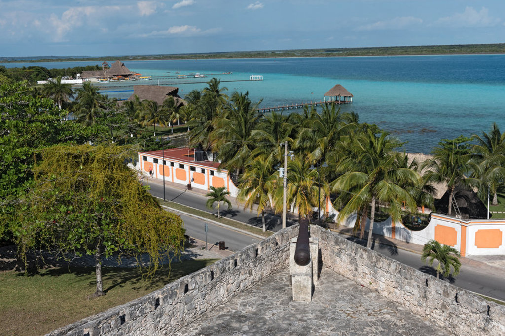 Uitzicht vanaf een fort op palmbomen en een turquoise lagune aan de Caribische kust van Mexico.