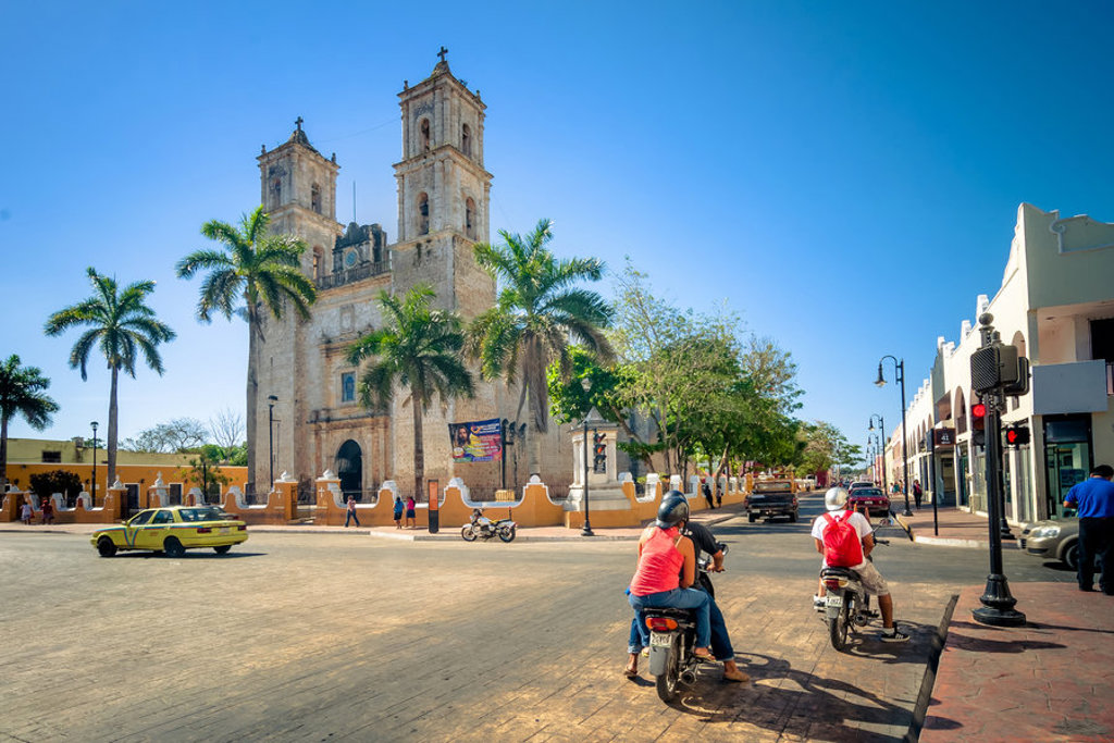 Straatbeeld met kathedraal en palmbomen tijdens 22-35ers reis Mexico.