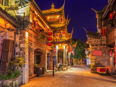 Verlichte straat met traditionele Chinese gebouwen en rode lantaarns tijdens de familiereisroute door China.