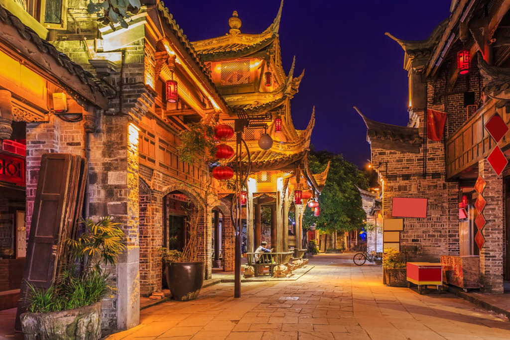 Verlichte straat met traditionele Chinese gebouwen en rode lantaarns tijdens de familiereisroute door China.