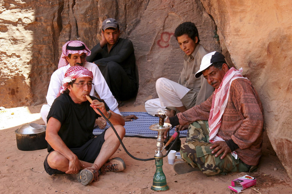 Mannen roken waterpijp en drinken thee in een rotsachtige kloof in Jordanië tijdens een groepsrondreis.