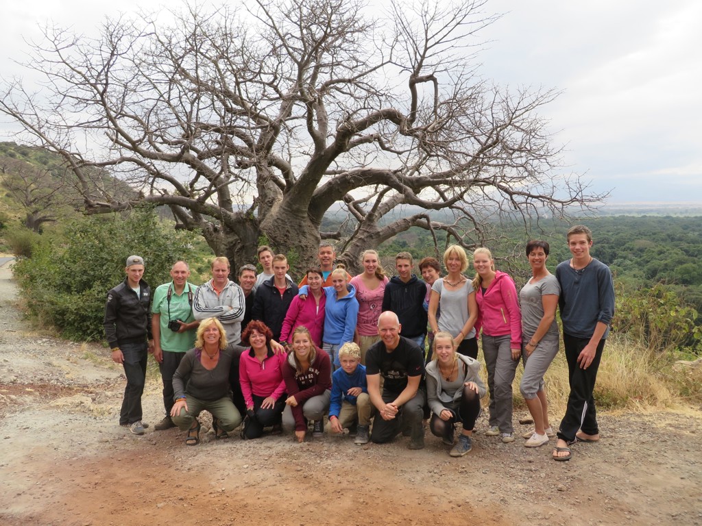 Groepsfoto van reizigers tijdens familiereis Tanzania en Zanzibar, bij een grote baobab in de wildernis.
