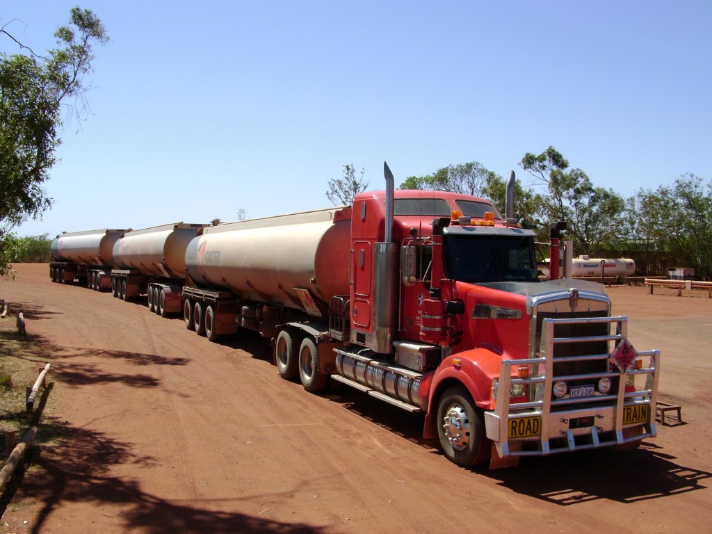 Rode road train met meerdere tanktrailers op een stoffige weg in de outback van Australië.