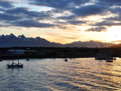 Zonsondergang boven de haven met zeilboten en besneeuwde bergen, startpunt van de route rondreis Antarctica.