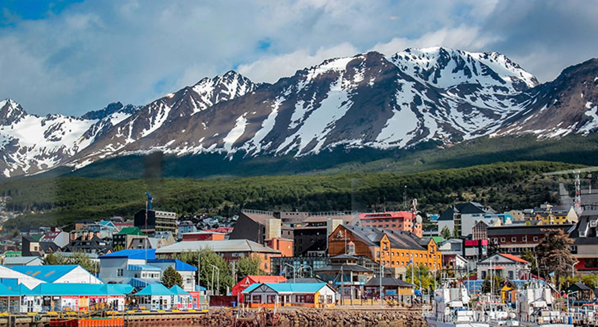 Uitzicht op Ushuaia met kleurrijke haven en besneeuwde Andesbergen op de achtergrond in Patagonië.