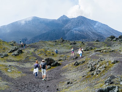 Wandelaars op lavaveld met uitzicht op een vulkaan tijdens de Route Ruta Maya.