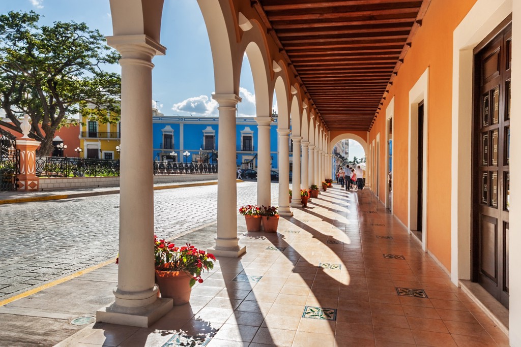Arcade met witte bogen en kleurrijke gevels in een koloniale straat in Mexico, tijdens groepsrondreis Mexico.