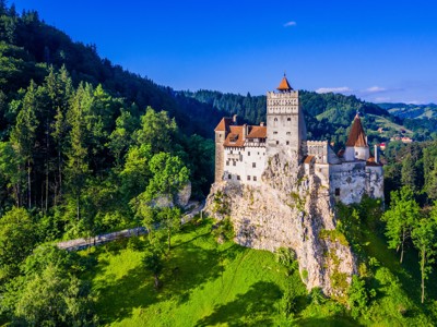 Kasteel Bran in Roemenië, hoog op een rots, omringd door groene bossen en heuvels.