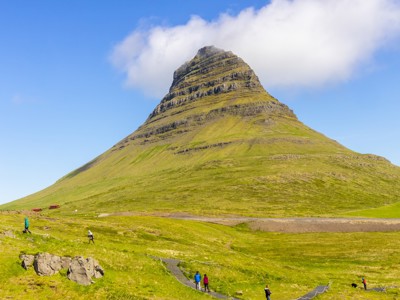 Kirkjufell-berg op het Snæfellsnes-schiereiland in IJsland, met wandelpad en groene hellingen onder een blauwe lucht.