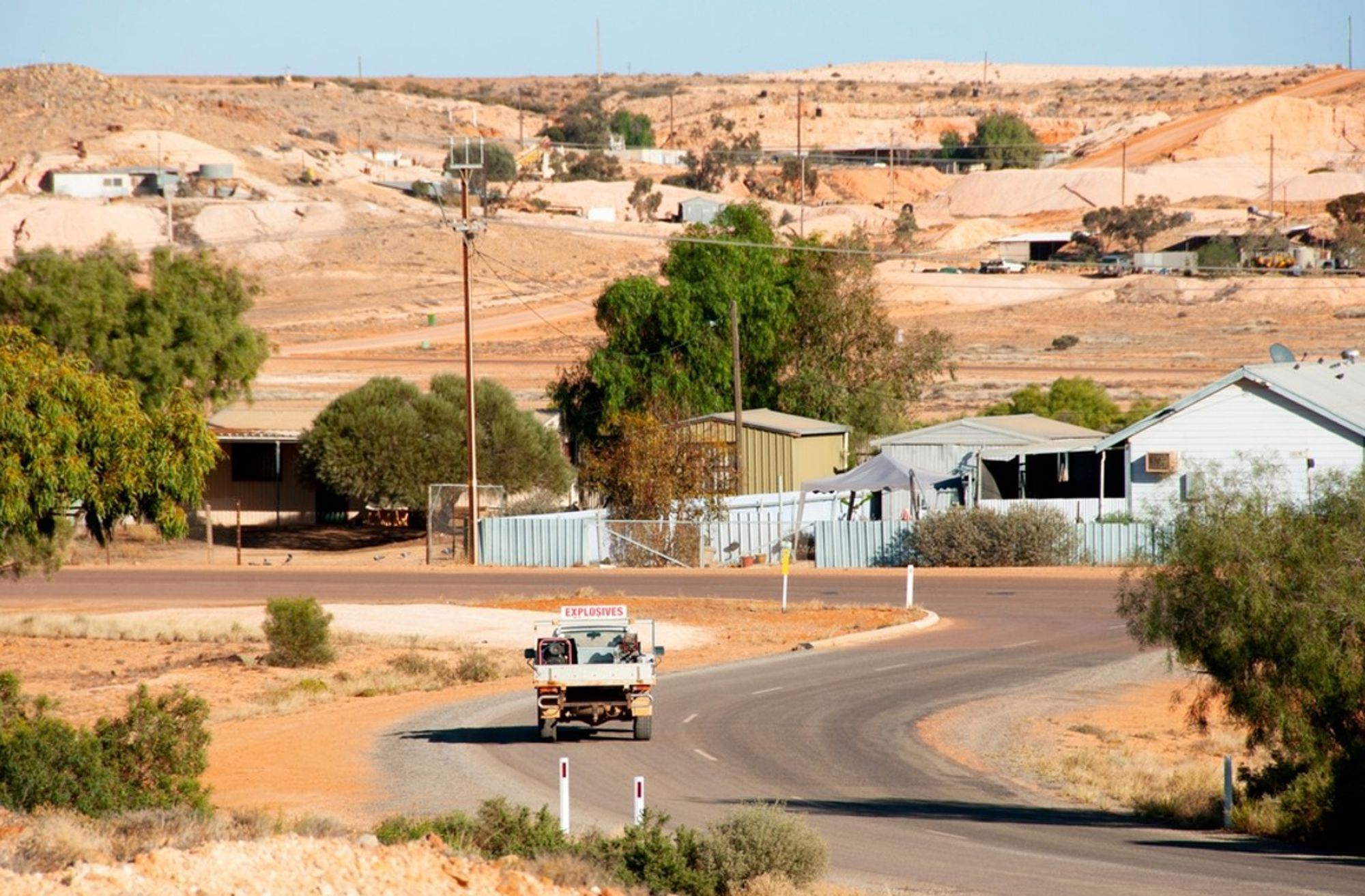 Vrachtwagen met ‘Explosives’ op een bochtige weg door een droog mijnstadje in de Australische outback.