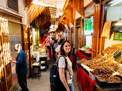 Reiziger in de medina van Marrakech langs kraampjes met dadels en noten tijdens de Route Marokko.
