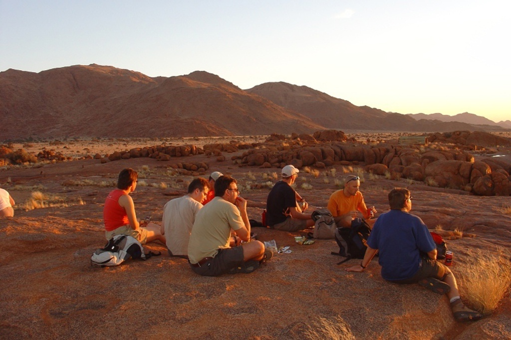 Reizigers pauzeren bij zonsondergang in een rotsachtig woestijnlandschap in Namibië, tijdens familiereis Namibië, Botswana en Zimbabwe.