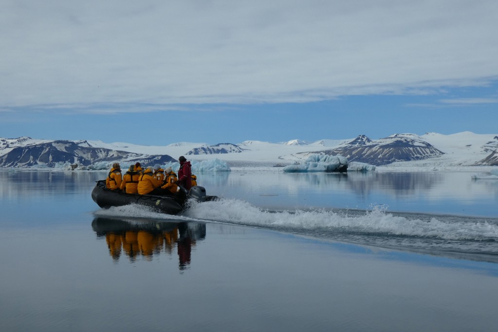Zodiacboot met reizigers op het stille poolwater langs ijsbergen en gletsjers in Spitsbergen.