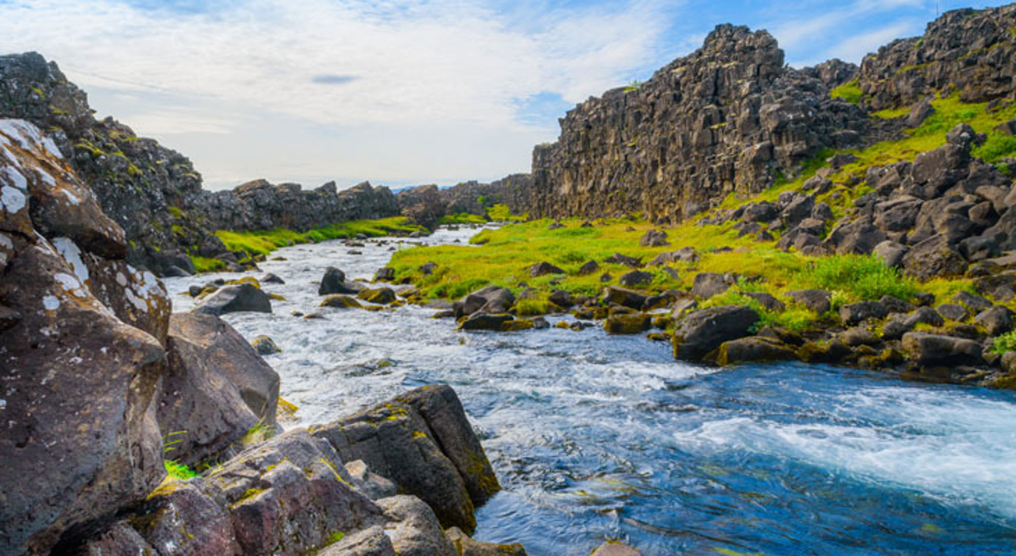 Rivier in een rotsachtig landschap met groene oevers in IJsland.