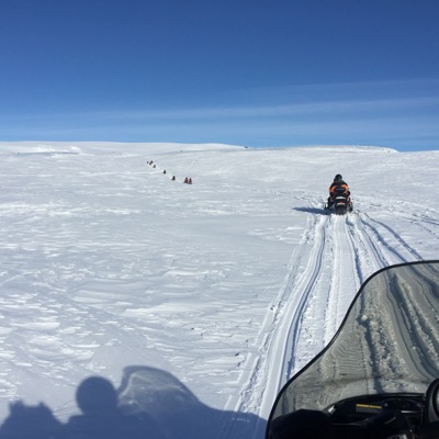 Sneeuwscootertour bij het Mývatn meer: sneeuwscooters rijden over een witte vlakte onder een blauwe lucht.