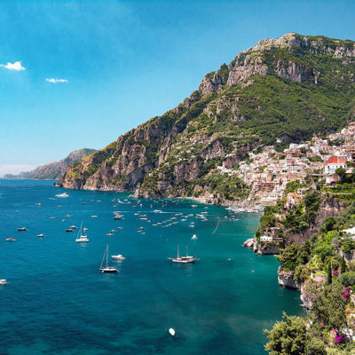 Uitzicht op Positano aan de Amalfikust met kleurrijke huizen op de kliffen en zeilboten in zee.