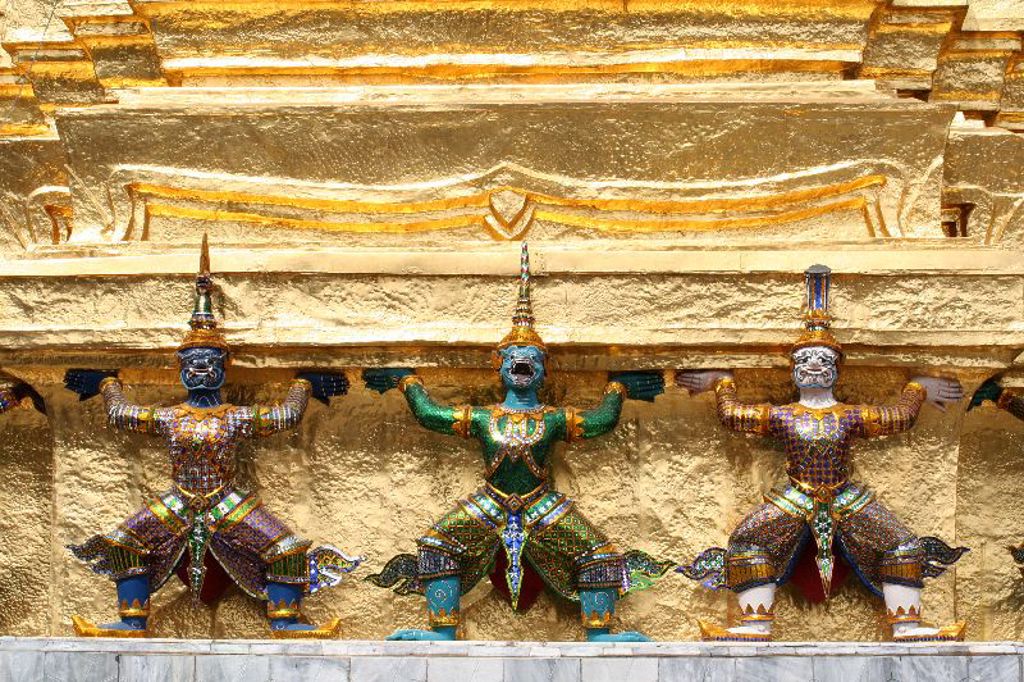 Gekleurde tempelwachters dragen een gouden tempelmuur bij een hoogtepunt van een groepsrondreis Thailand.