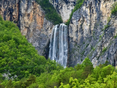 Waterval in een rotswand omringd door groen, tijdens een fietsvakantie in Slovenië.