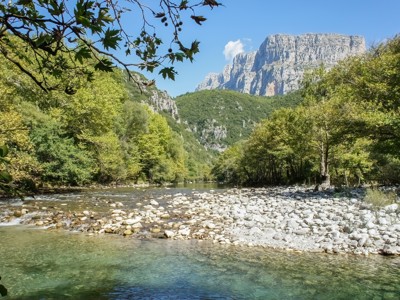 Rivier met kiezelstrand en groene vallei, met rotsmassief op de achtergrond tijdens de Route Griekenland.
