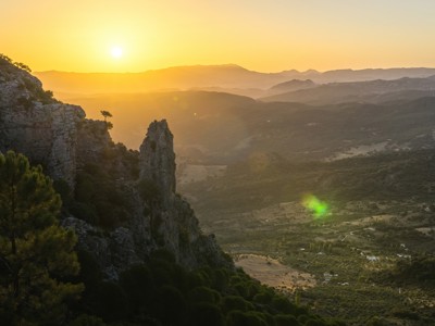 Zonsondergang boven berglandschap in Andalusië met rotskliffen en groene valleien.