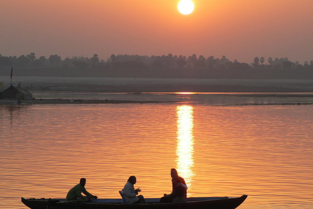 Zonsondergang boven de Ganges met bootje op het water tijdens groepsrondreis Noord-India en Nepal.