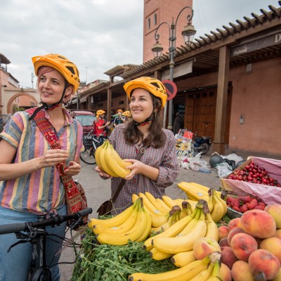 Fietsers met helm kopen fruit op een markt in Marokko tijdens een fietsvakantie.