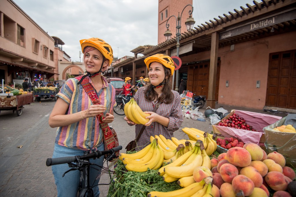 Fietsers met helm kopen fruit op een markt in Marokko tijdens een fietsvakantie.