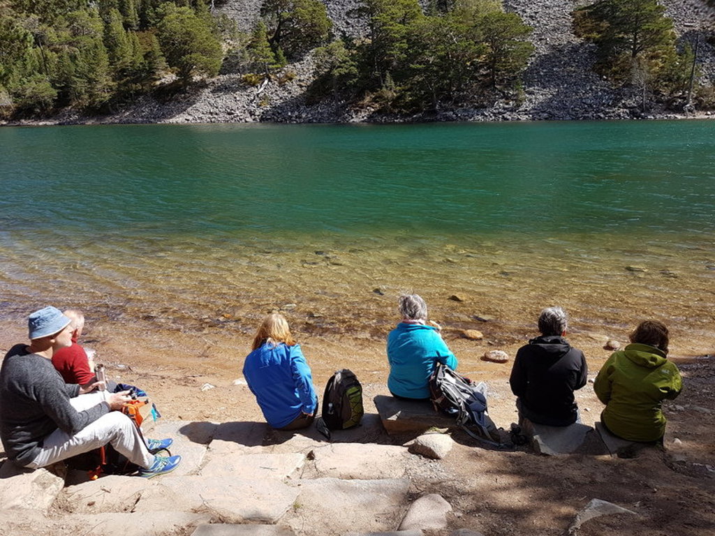 Reizigers pauzeren aan de oever van een loch in de Schotse Hooglanden tijdens een groepsrondreis Schotland.