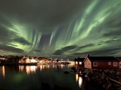 Noorderlicht boven een vissersdorp en water aan de Lofoten, Noorwegen.