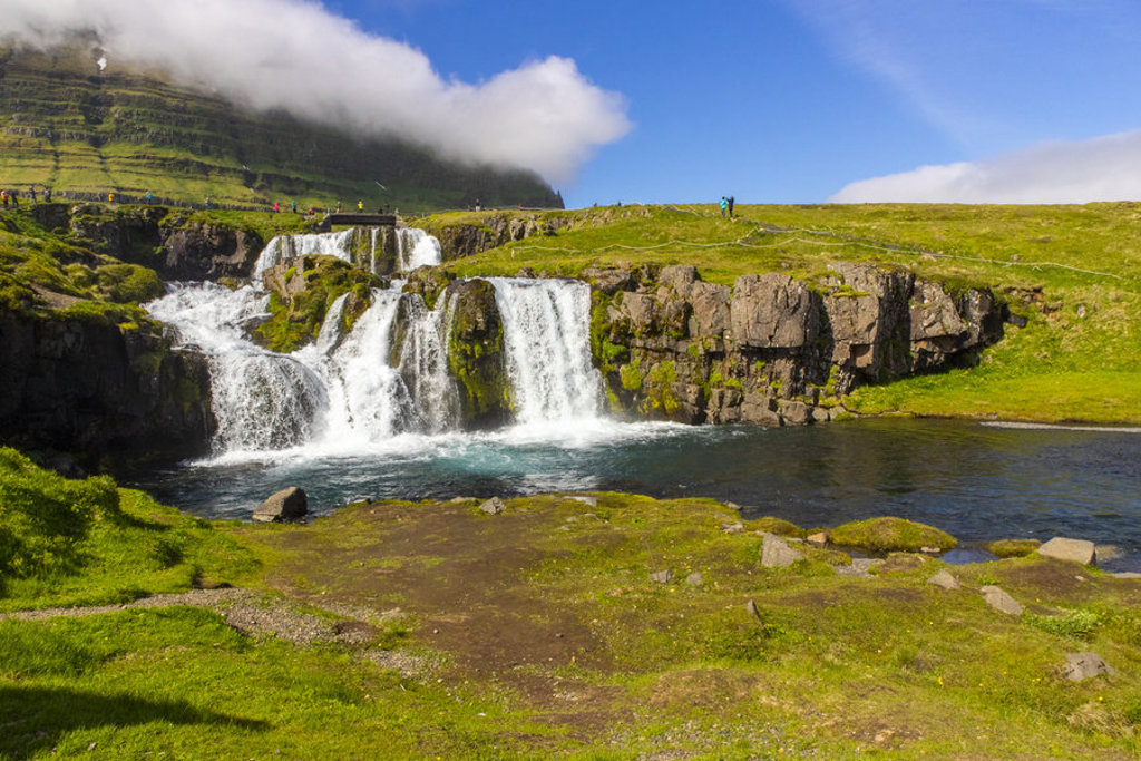 Waterval in groen IJslands landschap met rotsen en heldere rivier, tijdens groepsrondreis IJsland.