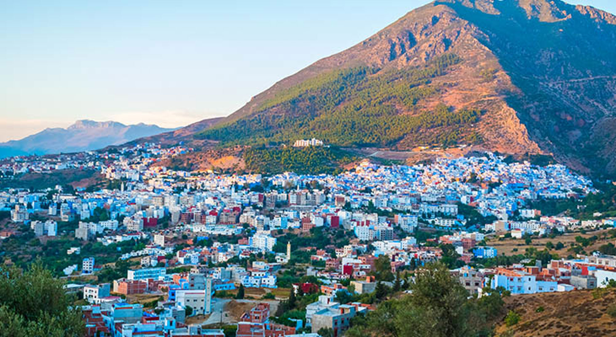 Panorama van Chefchaouen met blauwgeschilderde huizen tegen de Rifbergen in Marokko.