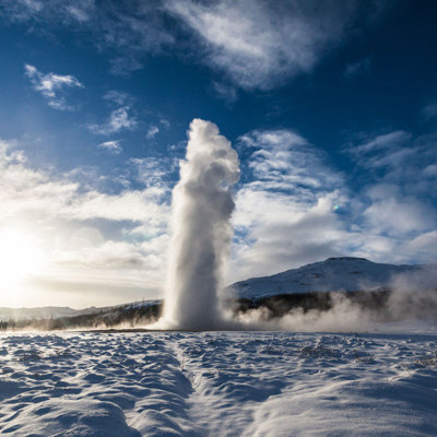 Geysir spuit heet water omhoog in een besneeuwd landschap tijdens een winter groepsrondreis door IJsland.