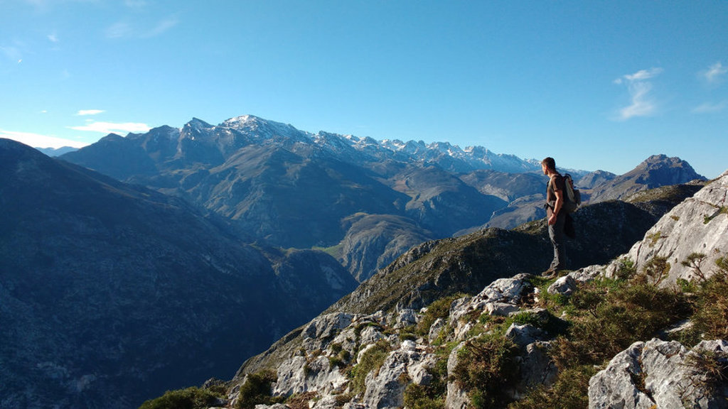 Wandelaar met rugzak kijkt uit over het berglandschap van de Picos de Europa in Spanje.