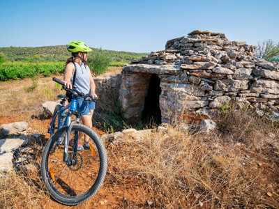Fietser met helm bij een stenen hut langs de route van de fietsvakantie Kroatië en de Balkan.