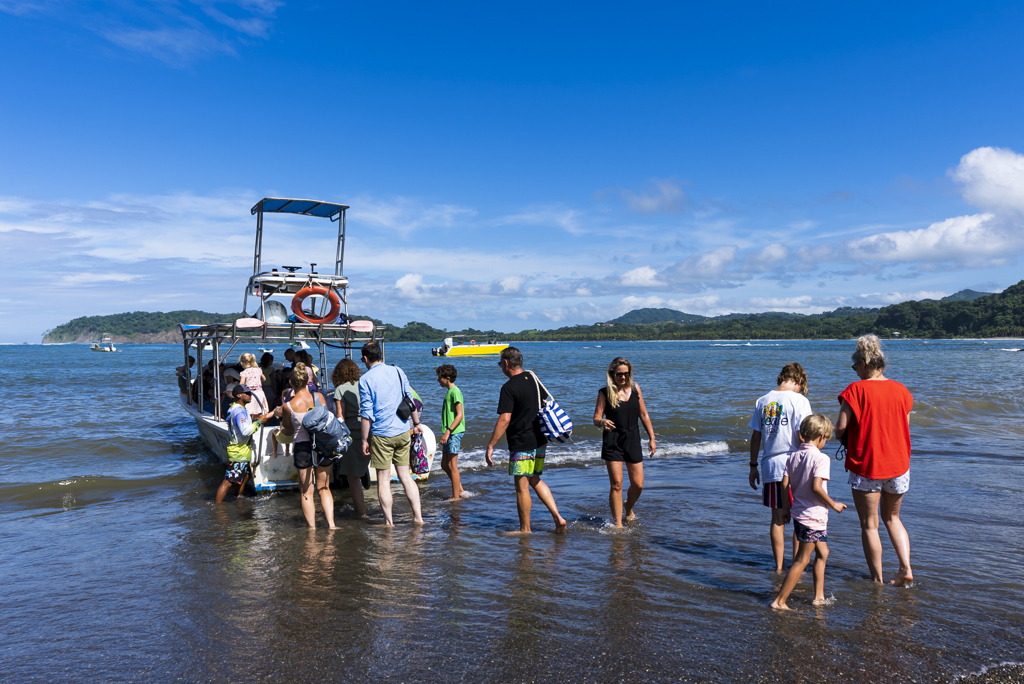 Gezinnen stappen vanaf het strand in een boot tijdens een familiereis Costa Rica.
