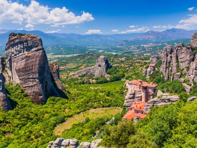 Uitzicht op de rotsformaties en kloosters van Meteora in Noord-Griekenland, met groene vallei en bergen.