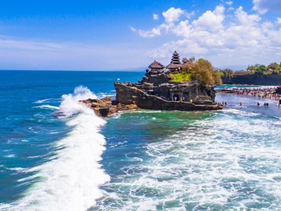 Tanah Lot zeetempel op een rots bij de kust van Bali, met golven en bezoekers.