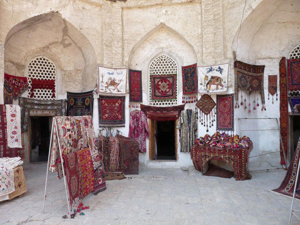 Tapijten en textiel in een traditionele bazaar in Oezbekistan tijdens een groepsrondreis langs de Zijderoute.