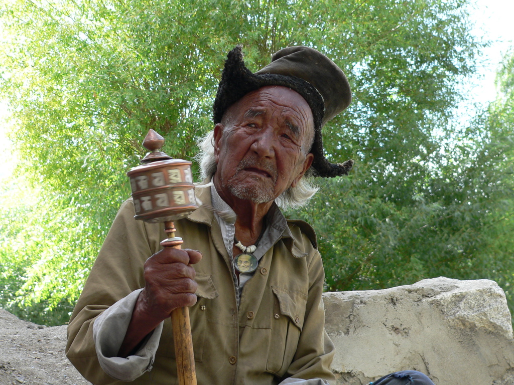 Oudere man in Ladakh met gebedsmolen, tijdens groepsrondreis India Spiti & Ladakh.