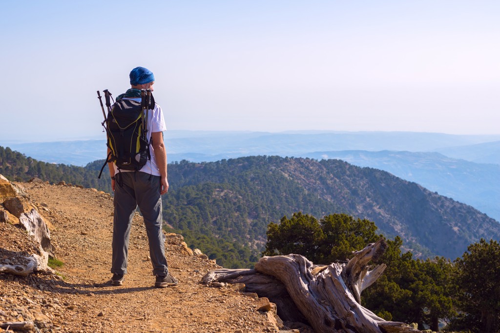 Wandelaar met rugzak op bergpad met uitzicht over de bergen van Cyprus tijdens een wandelvakantie.