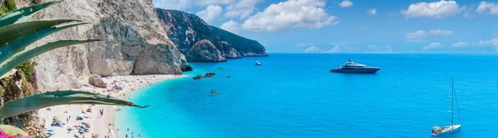Panorama van Porto Katsiki-strand op Lefkada met witte kliffen, turquoise zee en zeilboten.