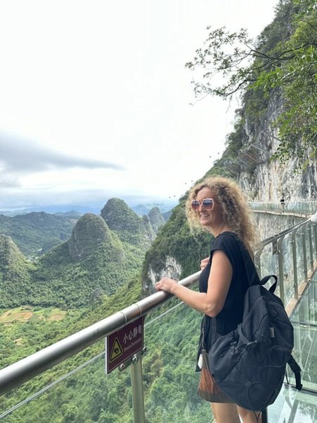 Reiziger op een glazen skywalk met uitzicht op karstbergen in China tijdens de groepsrondreis China Hoogtepunten.